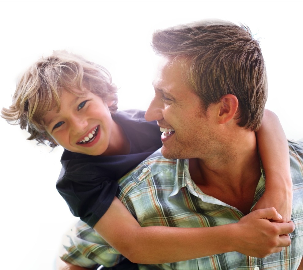 DadAndSon_WhiteBg_TightCrop Child with curly blonde hair smiling while being carried on the shoulders of a person in a plaid shirt, both against a bright white background.